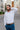 Man wearing a white dress shirt and blue pants on a city street.