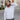 Man wearing a white dress shirt and blue pants on a city street.