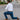 Man in a white shirt and blue pants performing a lunge on a street.
