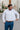 Man wearing a white dress shirt and blue pants outdoors.